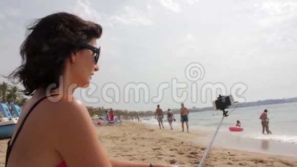 女孩用自拍棒在海边拍照视频的预览图
