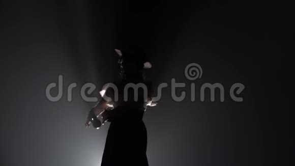女孩戴着帽子跳舞手里拿着石膏跳舞从后面的光烟雾背景慢动作视频的预览图