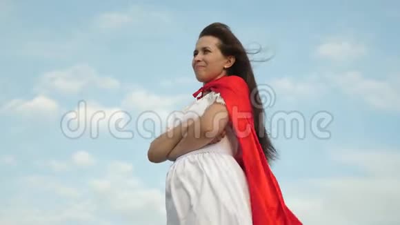 超级英雄女孩穿着红色斗篷站在田野上斗篷在风中飘扬特写镜头女孩梦想成为一个视频的预览图