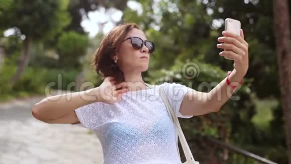 穿着白色连衣裙的女游客在智能手机上自拍视频的预览图
