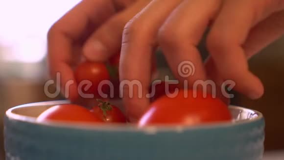 年轻的女人从碗里摘西红柿去洗厨房里视频的预览图