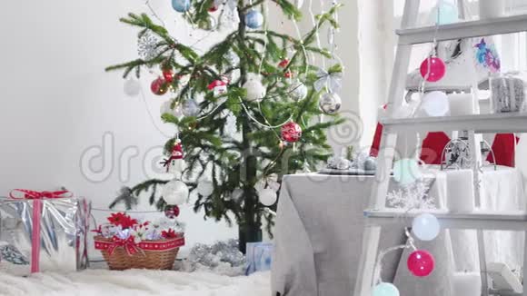 时尚的白色圣诞内部装饰杉树梯子礼品盒蜡烛靠窗慢动作视频的预览图