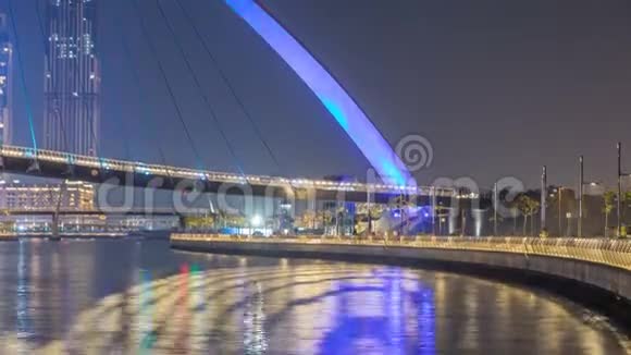 迪拜水上运河上空的未来派行人天桥在夜间时间推移阿联酋视频的预览图
