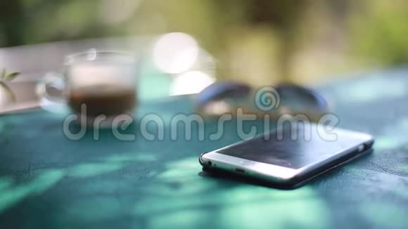 电话在桌子上咖啡和太阳镜通过模糊的游泳池与波克灯夏季工作构想视频的预览图