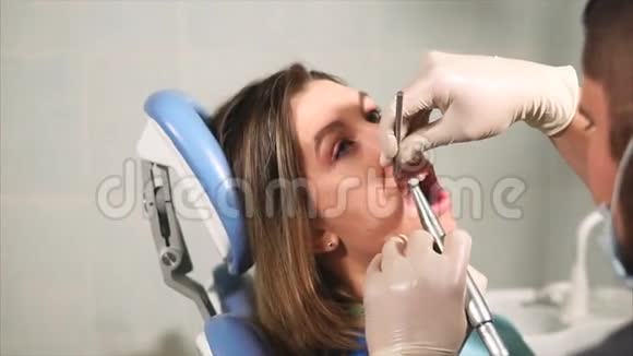 牙科医生为年轻女性清洁牙菌斑和牙垢视频的预览图
