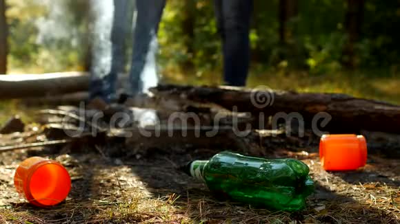 在前景的林间空地上有塑料瓶的垃圾火在冒烟人们走在里面视频的预览图