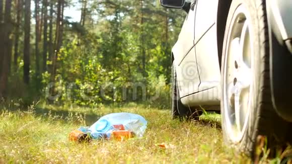 一个蓝色的袋子里装着塑料瓶的垃圾躺在汽车附近的大自然上塑料垃圾污染了大自然视频的预览图