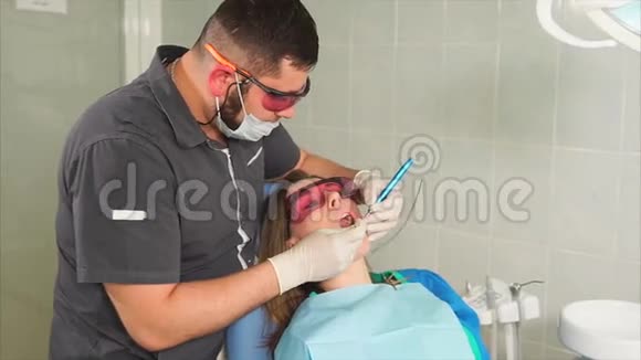 戴眼镜的牙齿矫正医生用激光给一个年轻女人美白牙齿视频的预览图