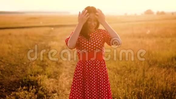 少女红衣羞涩笑草自然慢动作视频田野里的女孩害羞地微笑着夕阳穿着一件红色的裙子视频的预览图