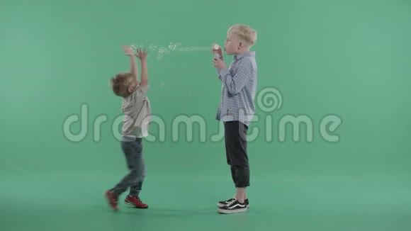 两个兄弟在绿色背景下玩肥皂泡视频的预览图