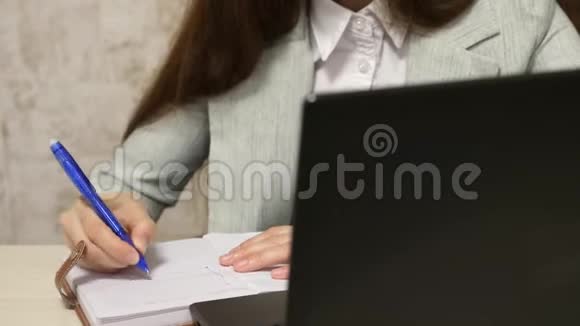 秘书在笔记本上写钢笔女孩坐在电脑办公室的椅子上在笔记本上做笔记年轻女性视频的预览图