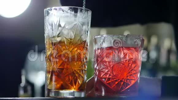 金属酒吧勺子将威士忌中的冰块混合在玻璃中背景不集中视频的预览图