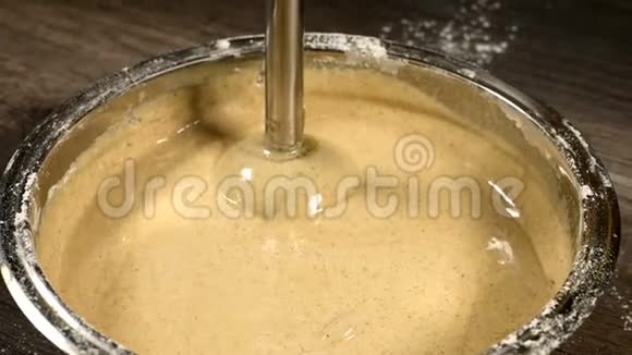 厨房里的一个糕点女孩在一个金属碗里特写用搅拌机敲打面团做海绵蛋糕家庭烹饪视频的预览图