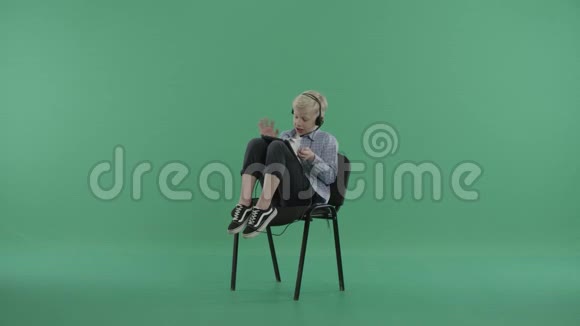 男孩坐在椅子上在平板电脑上通过Skype聊天视频的预览图