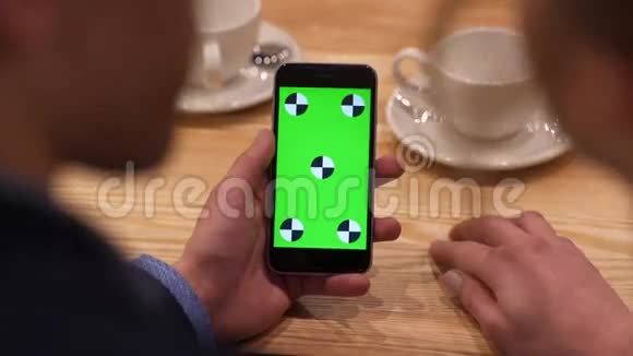 从空中看到玛娜她的手在手机的绿色屏幕上滑动男人坐在咖啡馆里的女人A玩得开心视频的预览图