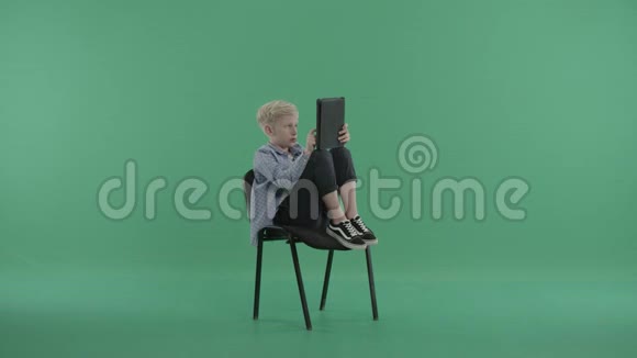小孩坐在椅子上在平板电脑上上网视频的预览图