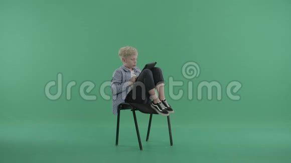 坐在椅子上的男孩腿上搭着一块平板电脑视频的预览图