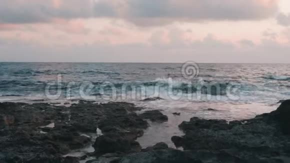 日落时波涛汹涌的大海黄昏时观海浪蓝色的海浪冲击着岩石海岸美丽的岩石海岸巨大的海浪撞击视频的预览图