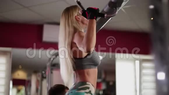健身房里的一个女人在教练的帮助下收紧横杆视频的预览图