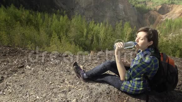 夏天一个女孩坐在山上从塑料瓶里喝水视频的预览图