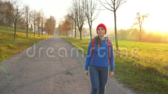 女旅行者背着背包在乡间的道路上行走欣赏周围的风景视频的预览图