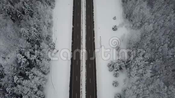 4K在冰冻的冬季森林里驾驶汽车飞越公路空中全景消失的视角视频的预览图