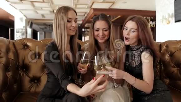 一群带着香槟的年轻女孩看着电话笑了视频的预览图