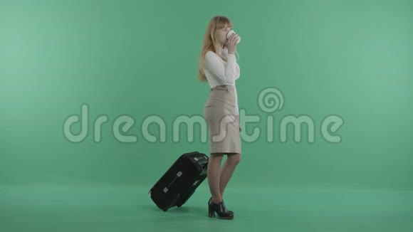 一个红头发的女人手里拿着咖啡和行李站着视频的预览图