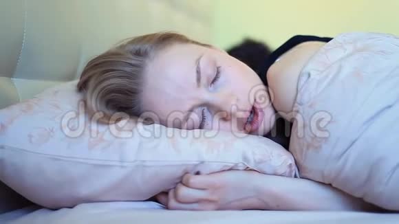 清晨醒来后蓝眼睛的年轻女子在床上打哈欠视频的预览图