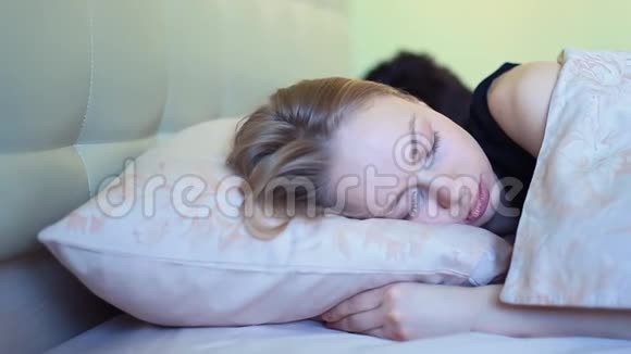 早睡的年轻女子在床上皱眉头视频的预览图