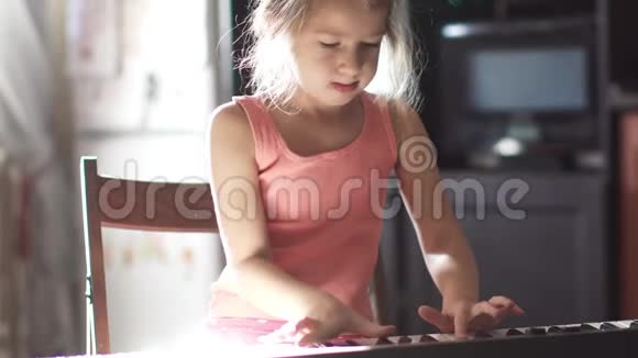 六岁的孩子学弹钢琴小可爱的小女孩在家玩合成器视频的预览图