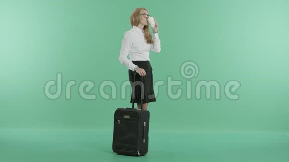 一个戴眼镜的女人拿着行李和咖啡站着视频的预览图