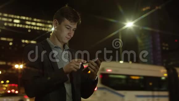 年轻的帅哥正在大街上用智能手机建立社交网络视频的预览图