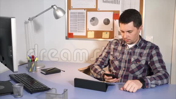 商人用手机和他的客户坐在他的办公室里视频的预览图