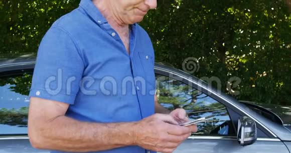 在汽车附近使用手机的老人视频的预览图