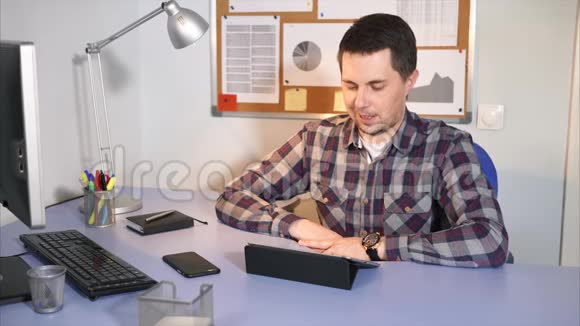 一个男人在工作休息时正在平板电脑上和他的女朋友聊天视频的预览图