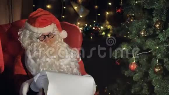 圣诞老人在圣诞树附近阅读新年礼物清单视频的预览图