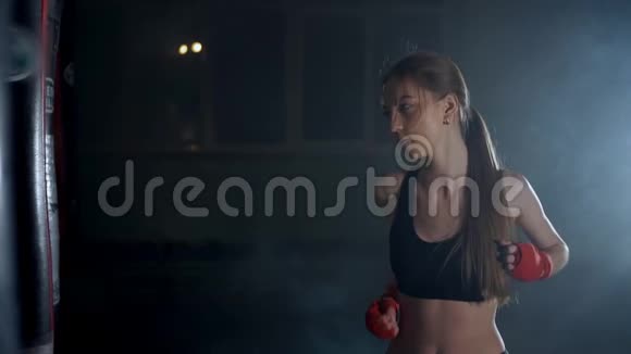 女孩年轻女子用拳击袋打拳击用跆拳道自卫视频的预览图