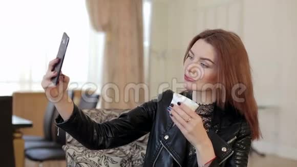 布鲁内特女孩在咖啡休息期间使用智能手机拍摄自拍照片视频的预览图