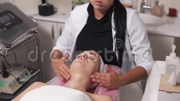 年轻女子正在和她的美容医生交谈同时躺在沙发上进行美容面部手术专业人员视频的预览图