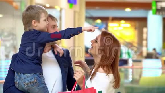 父母在贸易商场和儿子说话这家人在购物中心为圣诞节买东西快乐的父母视频的预览图