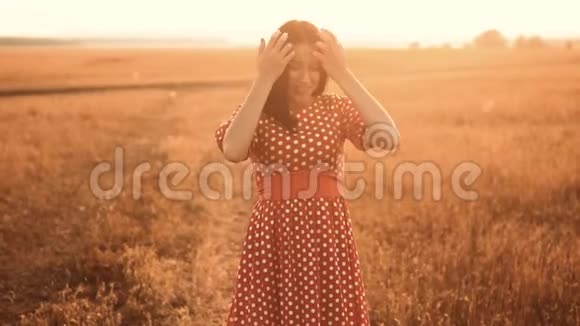 少女红衣羞涩笑草自然慢动作视频田野里的女孩害羞地微笑着夕阳穿着一件红色的裙子视频的预览图
