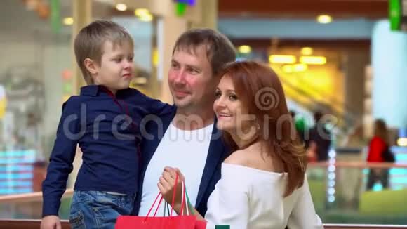 父母在贸易商场和儿子说话这家人在购物中心为圣诞节买东西快乐的父母视频的预览图