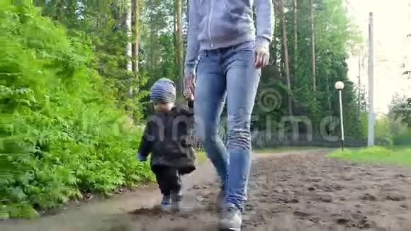 妈妈和宝宝在松林的乡间小路上散步关注可爱的小男孩视频的预览图