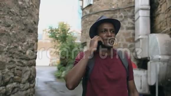 stadicam拍摄的非裔美国游客散步和聊天电话欧洲旅行的快乐青年视频的预览图