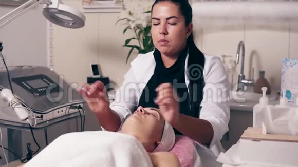 女性美容师正在水疗沙龙做颈部按摩年轻女子闭着眼睛躺在沙发上视频的预览图