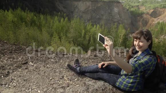 年轻女子在山里用她的智能手机自画像视频的预览图