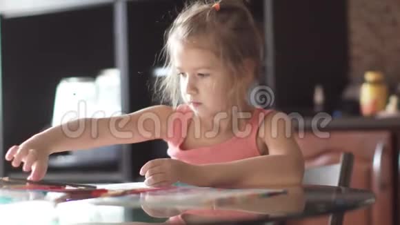 六岁的孩子坐在一张桌子旁画房子清晨阳光下的小女孩视频的预览图