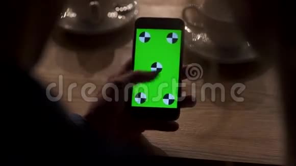 女性特写镜头把照片放大到绿色屏幕手机上伙计s手拿手机视频的预览图