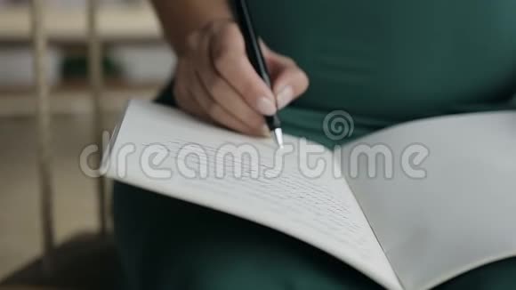 一位年轻女子在笔记本上用黑色钢笔写纸条视频的预览图